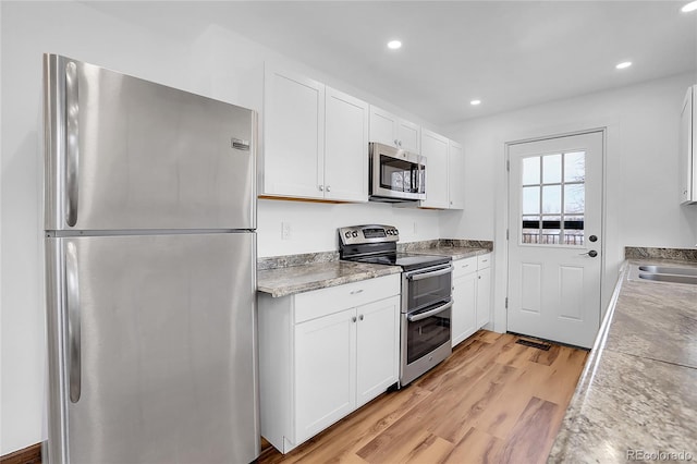 kitchen with light wood-style floors, white cabinetry, stainless steel appliances, and light countertops