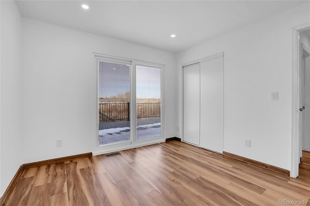 spare room featuring light wood-type flooring, visible vents, baseboards, and recessed lighting