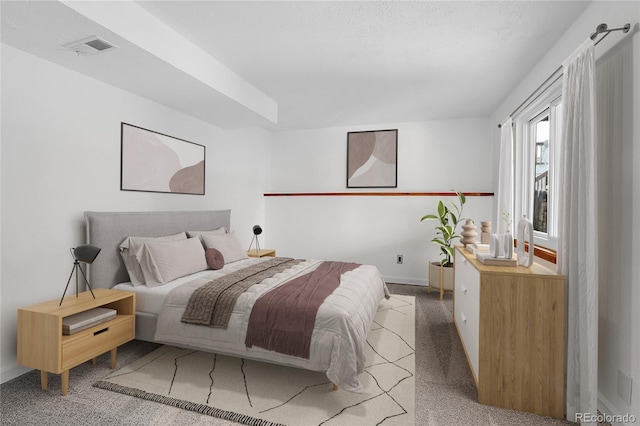 bedroom with carpet, visible vents, a textured ceiling, and baseboards