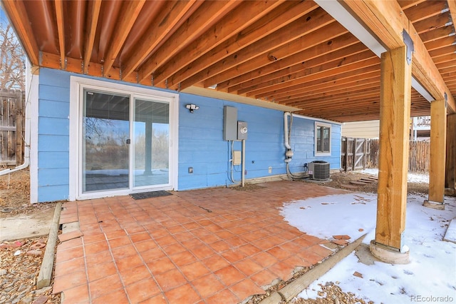 snow covered patio with central AC and fence