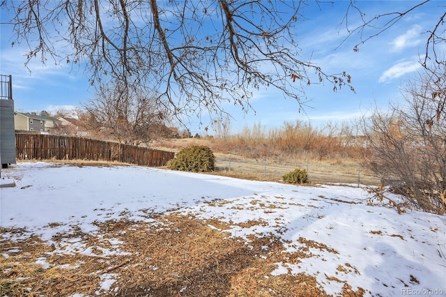 yard layered in snow featuring fence