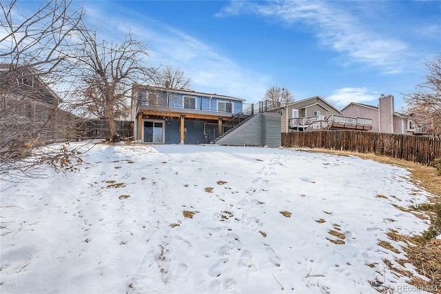 snow covered house featuring fence and a wooden deck