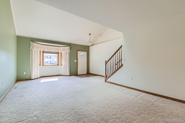 carpeted foyer with vaulted ceiling, stairway, and baseboards