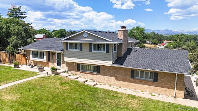 9629 Yukon Ct, Westminster, CO 80021 - tri-level home featuring a chimney, brick siding, a patio area, and a mountain view