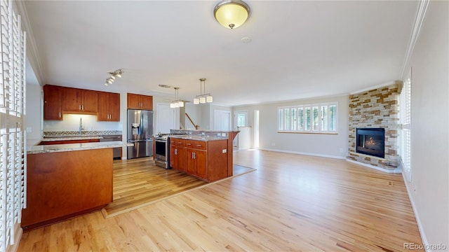 9629 Yukon Ct, Westminster, CO 80021 - kitchen with stainless steel appliances, ornamental molding, light wood finished floors, open floor plan, and a stone fireplace