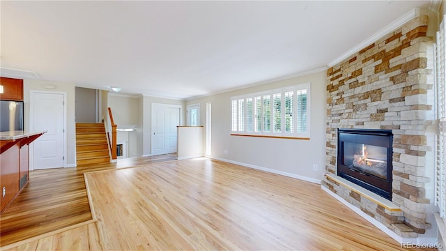 9629 Yukon Ct, Westminster, CO 80021 - unfurnished living room with light wood-style floors, ornamental molding, stairs, and a fireplace