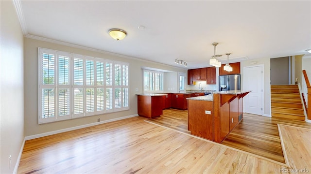 9629 Yukon Ct, Westminster, CO 80021 - kitchen featuring stainless steel fridge, ornamental molding, light wood-style floors, a kitchen bar, and hanging light fixtures