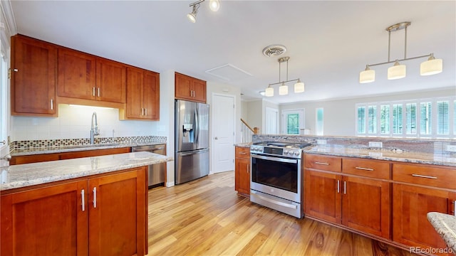 9629 Yukon Ct, Westminster, CO 80021 - kitchen with stainless steel appliances, light wood-type flooring, hanging light fixtures, and brown cabinetry