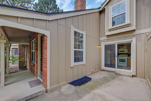 2713 W Long Dr Unit C, Littleton, CO 80120 - doorway to property featuring board and batten siding, a chimney, and a patio