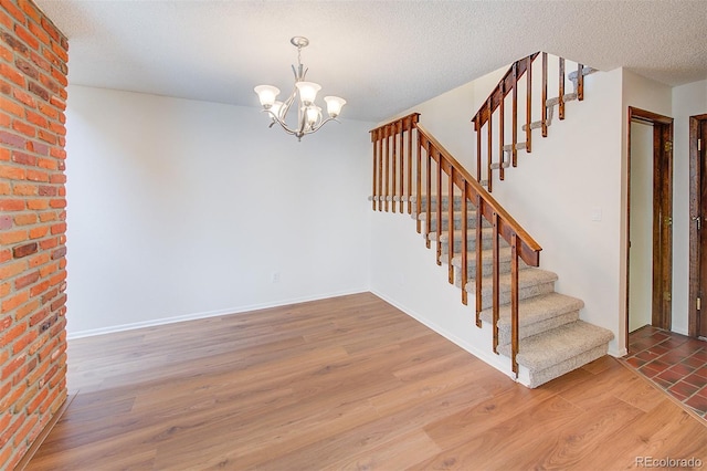 2713 W Long Dr Unit C, Littleton, CO 80120 - staircase featuring wood finished floors, a chandelier, and a textured ceiling