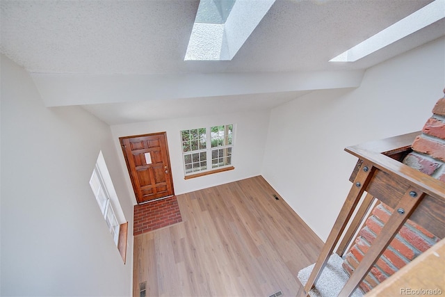 2713 W Long Dr Unit C, Littleton, CO 80120 - foyer with a skylight, light wood-style flooring, vaulted ceiling, and a textured ceiling