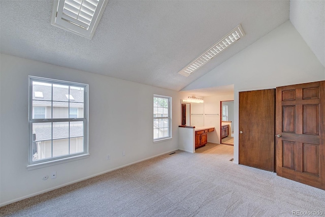 2713 W Long Dr Unit C, Littleton, CO 80120 - unfurnished bedroom with light carpet, vaulted ceiling, ensuite bath, and a textured ceiling
