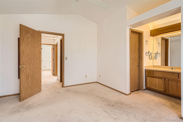 unfurnished bedroom featuring ensuite bath, lofted ceiling, sink, and light carpet