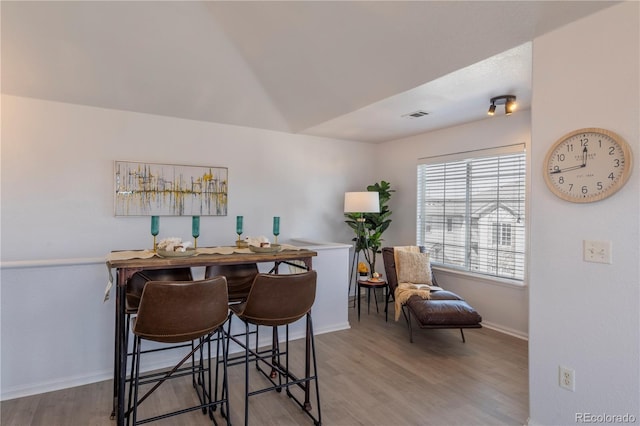 dining space featuring wood finished floors, visible vents, and baseboards