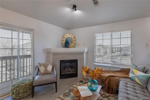 living area with visible vents, wood finished floors, and a glass covered fireplace