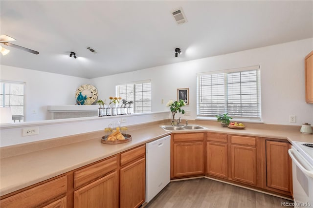 kitchen with a sink, visible vents, white appliances, and light countertops