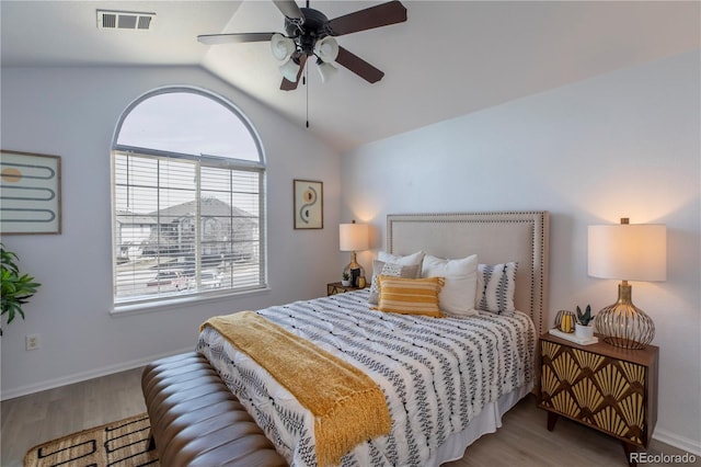 bedroom featuring visible vents, baseboards, lofted ceiling, wood finished floors, and a ceiling fan