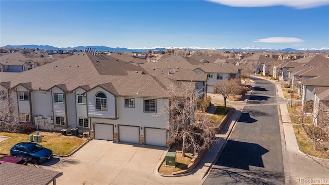 view of front of home featuring a mountain view, a residential view, concrete driveway, an attached garage, and a shingled roof