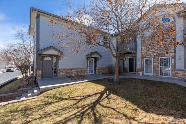 3260 E 103rd Pl Unit 912, Thornton, CO 80229 - view of front of property featuring stone siding, a balcony, and a front lawn