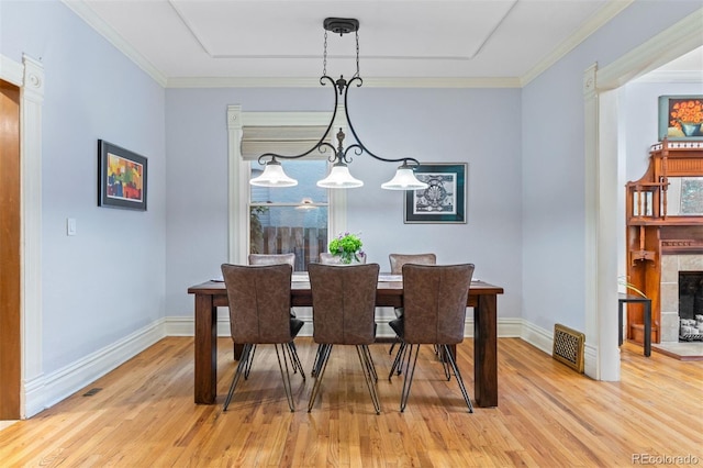 848 S Emerson St, Denver, CO 80209 - dining area with light wood-type flooring, baseboards, a fireplace with raised hearth, and crown molding