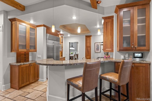 848 S Emerson St, Denver, CO 80209 - kitchen with brown cabinetry, a peninsula, stone tile flooring, a kitchen breakfast bar, and baseboards