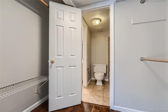 bathroom featuring wood-type flooring, a textured ceiling, and toilet