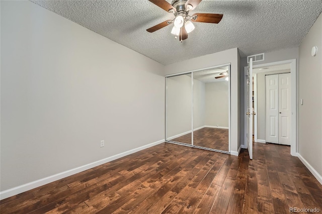 unfurnished bedroom with a closet, dark hardwood / wood-style floors, ceiling fan, and a textured ceiling