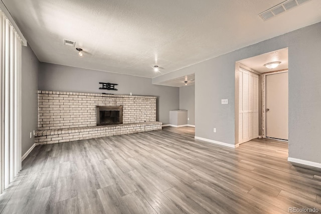 16623 E Asbury Pl, Aurora, CO 80013 - unfurnished living room with wood finished floors, a textured ceiling, and a brick fireplace