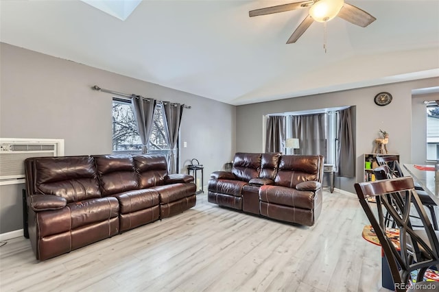 living room featuring ceiling fan, plenty of natural light, lofted ceiling with skylight, and light wood-type flooring