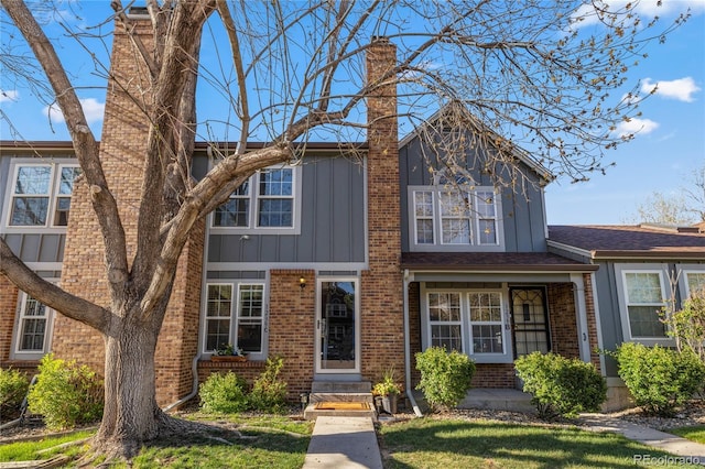 view of front of house featuring a chimney, brick siding, and board and batten siding