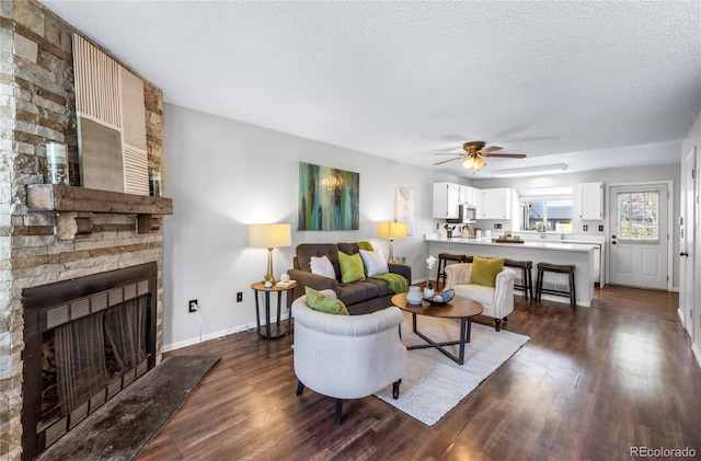 living area with dark wood finished floors, ceiling fan, and a textured ceiling
