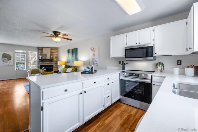 kitchen featuring dark wood-style flooring, light countertops, a peninsula, and appliances with stainless steel finishes