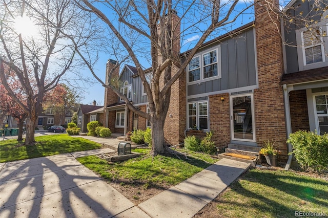 multi unit property with a chimney, board and batten siding, a residential view, and brick siding