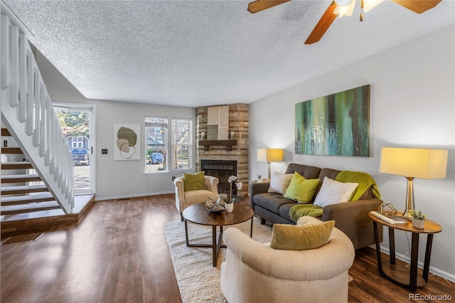 living area featuring a textured ceiling, stairway, wood finished floors, and a fireplace