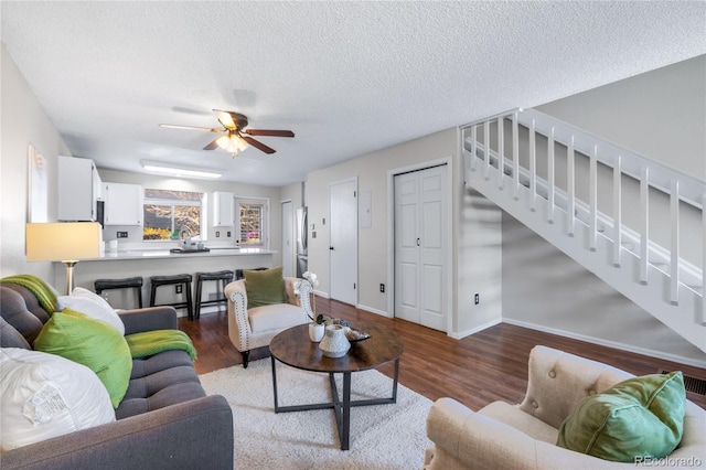 living room featuring baseboards, stairway, wood finished floors, and a ceiling fan