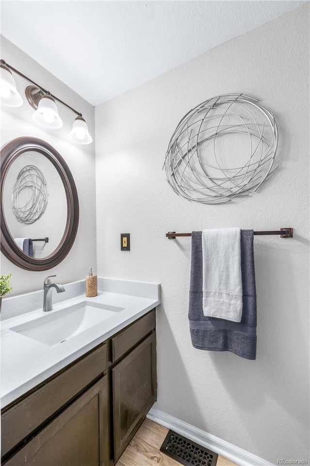bathroom with vanity, baseboards, visible vents, and wood finished floors