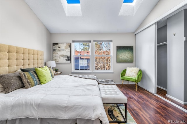 bedroom with lofted ceiling with skylight, baseboards, a closet, and wood finished floors
