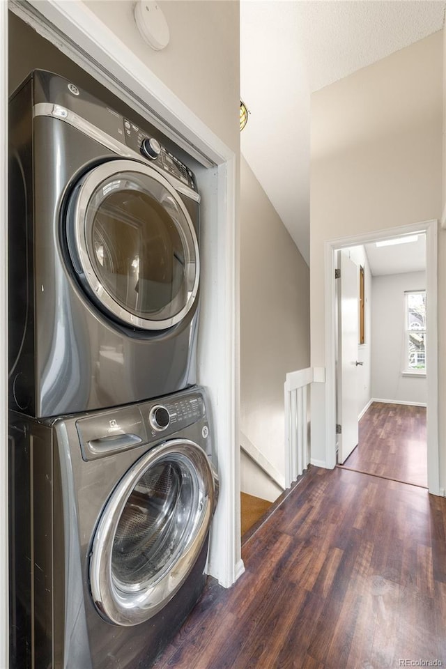 laundry room featuring baseboards, stacked washing maching and dryer, laundry area, and wood finished floors