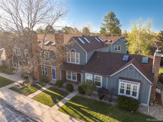 view of front of house featuring a chimney, board and batten siding, a residential view, and a front yard