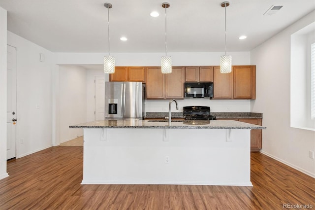 9674 Truckee St, Commerce City, CO 80022 - kitchen featuring range with gas stovetop, stainless steel fridge, brown cabinets, and black microwave