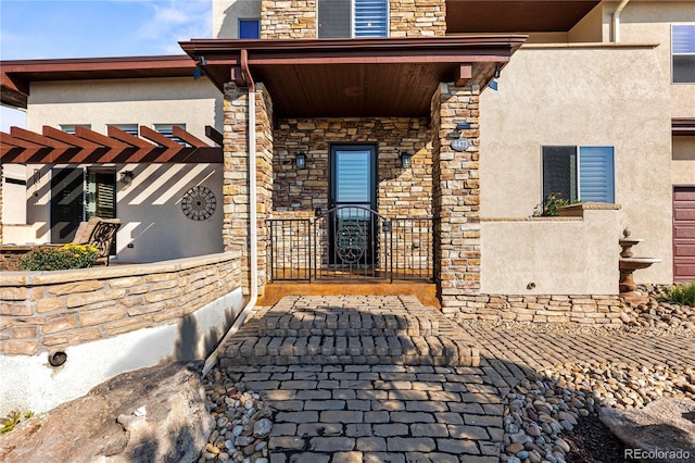 doorway to property with stone siding, a porch, and stucco siding