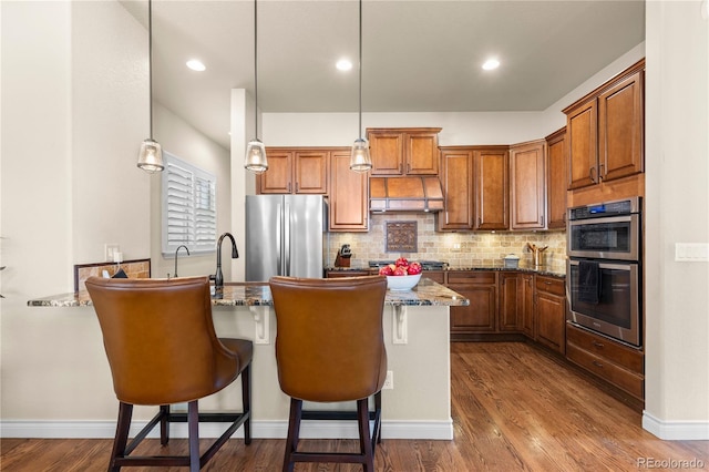 kitchen with dark stone countertops, a breakfast bar area, backsplash, and appliances with stainless steel finishes