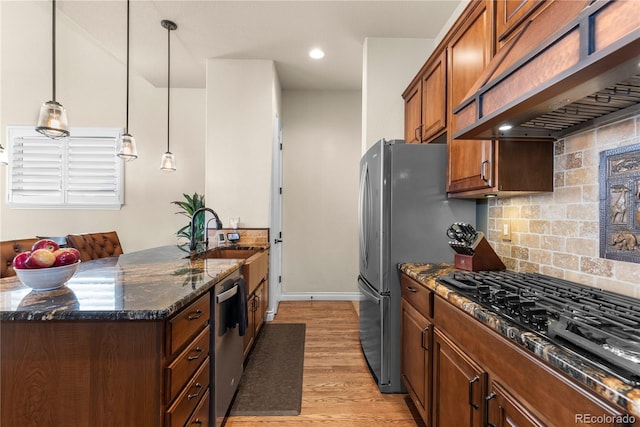 kitchen featuring a sink, tasteful backsplash, a peninsula, custom range hood, and light wood-style floors