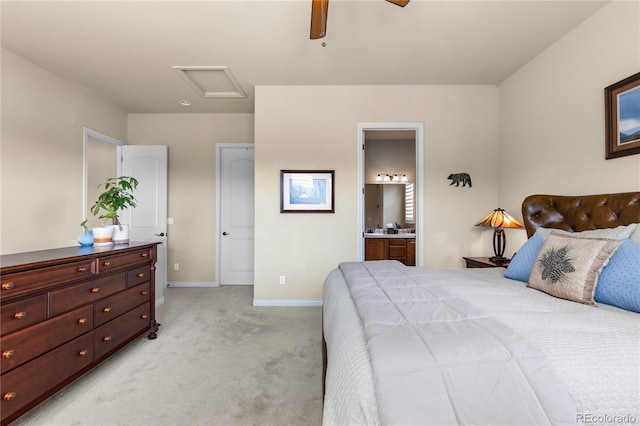 bedroom with connected bathroom, a ceiling fan, attic access, light carpet, and baseboards