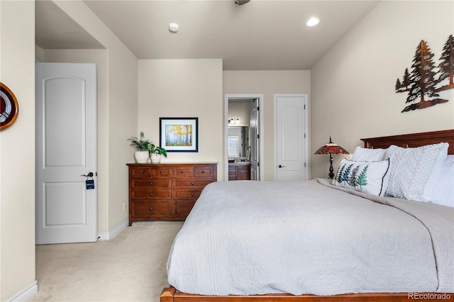 bedroom featuring baseboards, ensuite bath, and light carpet