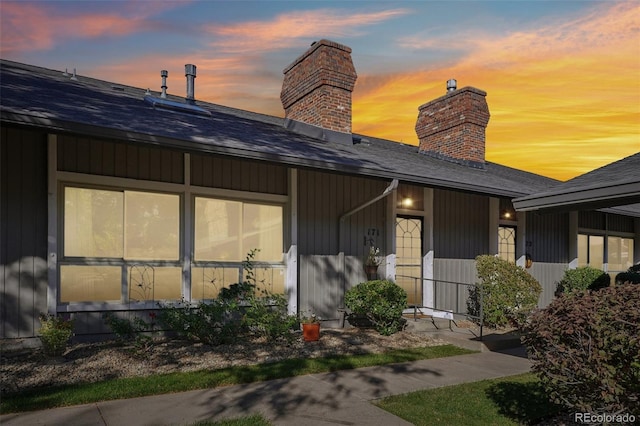 exterior space with roof with shingles and a chimney