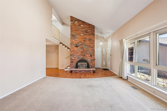 unfurnished living room featuring visible vents, baseboards, carpet, stairs, and high vaulted ceiling