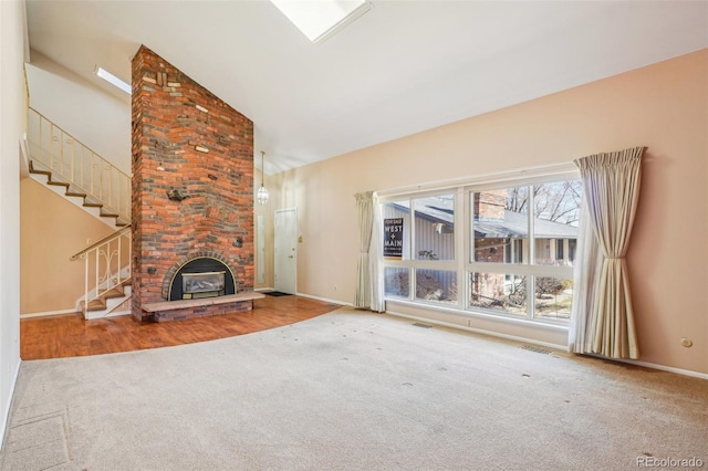 unfurnished living room with high vaulted ceiling, a fireplace, carpet flooring, visible vents, and stairway