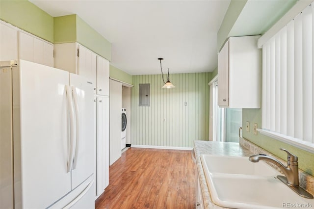 kitchen featuring light wood finished floors, freestanding refrigerator, white cabinetry, a sink, and electric panel