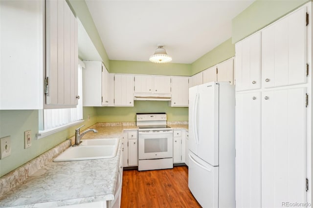 kitchen with light countertops, dark wood-type flooring, a sink, white appliances, and under cabinet range hood